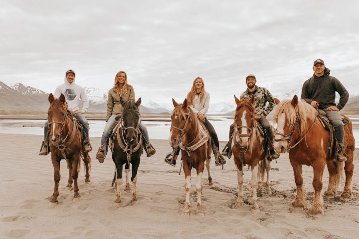 a group of people riding horses on a beach